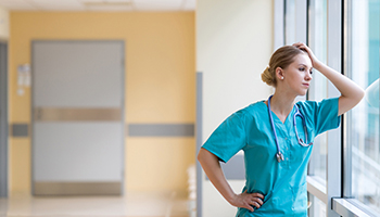 Tired female nurse in hospital corridor