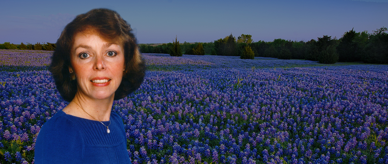 Attorney standing in a field of bluebonnets, surrounded by vibrant purple and blue flowers under a clear blue sky.