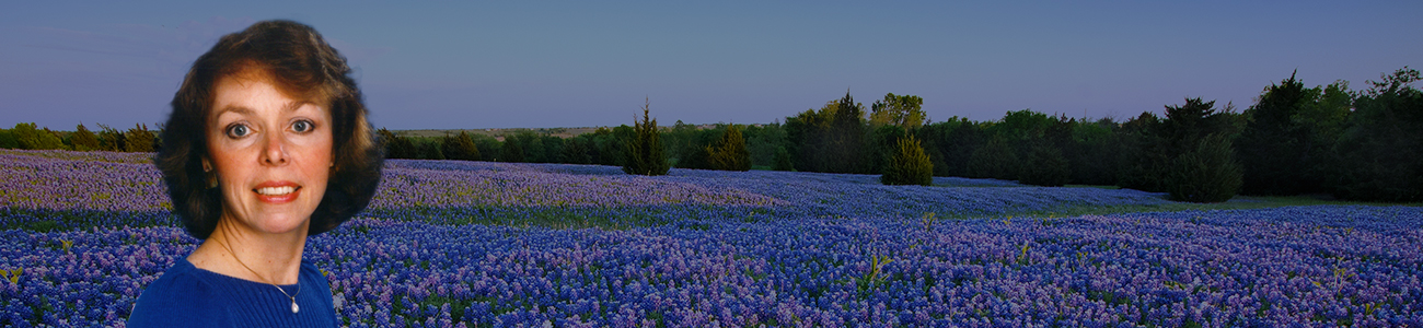 Attorney standing in a field of bluebonnets, surrounded by vibrant purple and blue flowers under a clear blue sky.